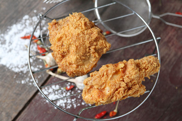 Fried Chicken on sieve, powder on wooden floor background.