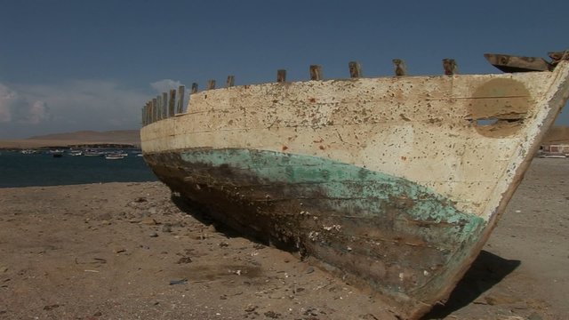 Old fishing boat in desert of Paracas National Park, Peru