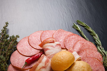 plate of sliced sausage, peppers, herbs and French bread rolls o