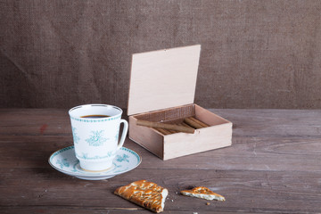 Porcelain cup of coffee, a box of cigarillos and cookies on old