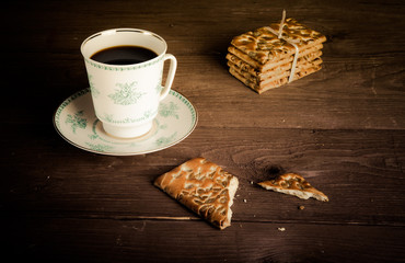 Porcelain cup of coffee and stack of cookies on old wooden table