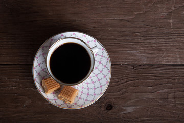 Top view to porcelain cup of coffee with toffee on old wooden ta