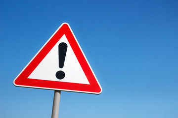 Warning road sign against a blue sky.