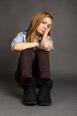 Sulky teenage girl sitting on the floor - obrazy, fototapety, plakaty