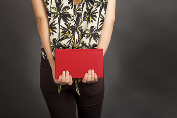 Back view of young student woman holding a red  book
