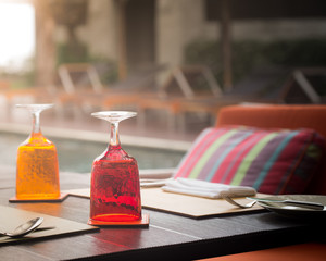 Red and Yellow Glass of water on luxury table setting near swimm