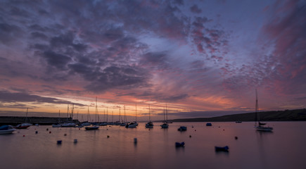 Fototapeta na wymiar Golden sunrise over a harbour with small boats and yachts 