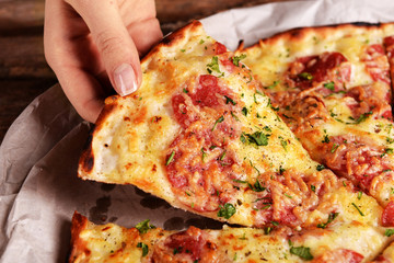 Female hand holding slice of pizza close up