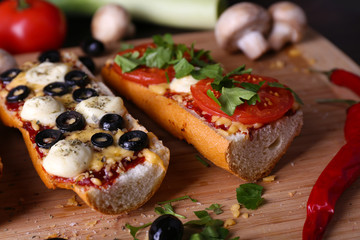 Different sandwiches with vegetables and cheese on cutting board on table close up