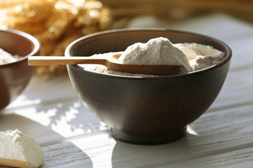 Flour in bowls on wooden planks background