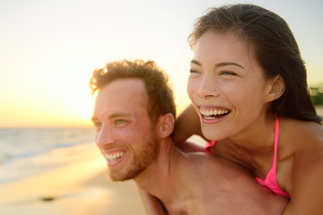 Beach couple laughing in love having fun romance