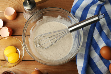Preparation cream with eggs in glass bowl on wooden background