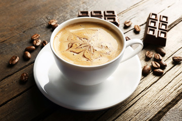Cup of coffee latte art with grains and chocolate on wooden background