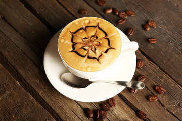 Cup of coffee latte art with grains on wooden background