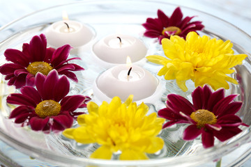 Obraz na płótnie Canvas Bowl of spa water with flowers and candles, closeup