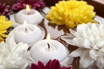Bowl of spa water with flowers and candles, closeup
