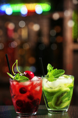 Glasses of cocktails in bar on bright blurred background