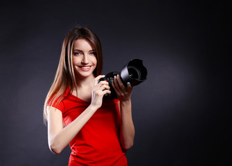 Young female photographer taking photos on black background