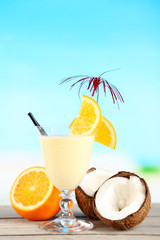 Glass of summer cocktail on wooden table on bright blurred background