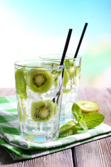 Glasses of cocktails on wooden table on bright blurred background