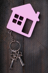 Toy house with key on wooden background