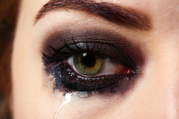 Eye of young woman with tear drop close up