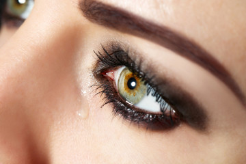 Obraz premium Eye of young woman with tear drop close up