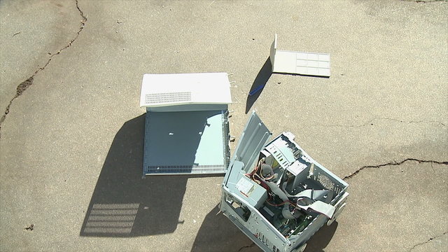 Computer Crash Fail. An old personal computer crashes onto concrete and breaks apart. Shot in slow motion at 60fps.