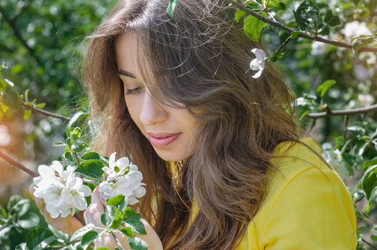 beautiful young brunette woman in the blossoming spring garden
