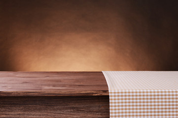 Empty wooden table with napkin and brown background