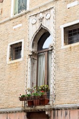 Fototapeta na wymiar Typical venetian balcony with flower pot over channel
