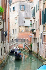 Fototapeta na wymiar Venetian Channel with gondola and small bridge