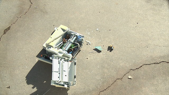 Flying Fax Falls Apart. An old fax machine crashes down onto concrete, breaking apart. Shot in slow motion at 60fps.