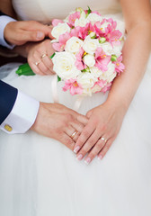 Obraz na płótnie Canvas Wedding couple holding hands with a bouquet of flowers