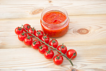 Tomatoes and tomato sauce on a wooden table.