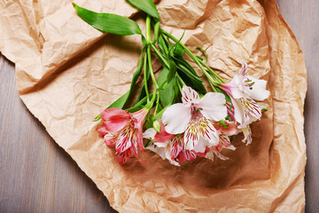 Beautiful Alstroemeria on parchment on wooden table, top view