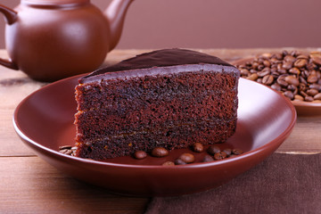 Delicious chocolate cake with coffee beans on plate on table close up