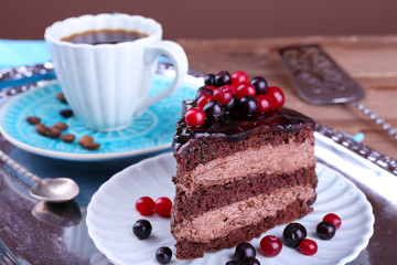 Delicious chocolate cake with berries and cup of coffee on table close up