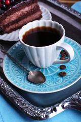 Delicious chocolate cake with berries and cup of coffee on table close up