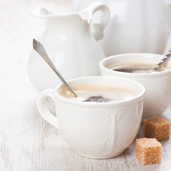 Cup of coffee with sugar cubs and milk jug