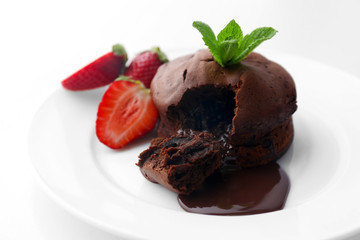 Chocolate fondant with strawberries on white plate, closeup