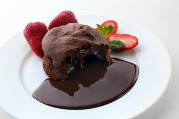 Chocolate fondant with strawberries on white plate, closeup