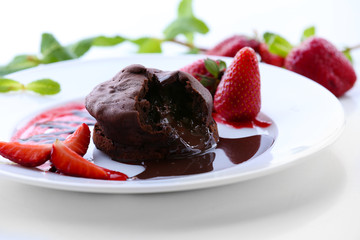 Chocolate fondant with strawberries on white plate, closeup