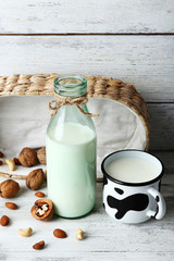 Milk in glassware and walnuts on wooden background