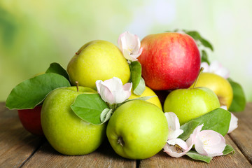Fresh apples with apple blossom on wooden table, on nature background