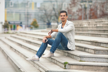 Obraz premium Smiling young man sitting on the stairs