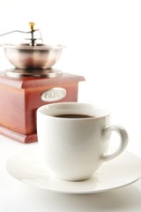 Cup of coffee with saucer and mill on white