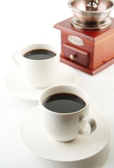 Cups of coffee with saucer and mill on white