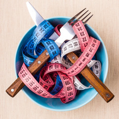 Many colorful measuring tapes in bowl on table