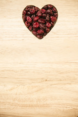 dried cranberry fruit heart shaped on wood board